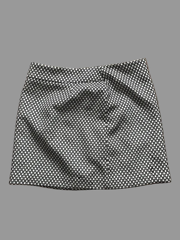 A black and white patterned mini skirt laid flat on a wooden floor.