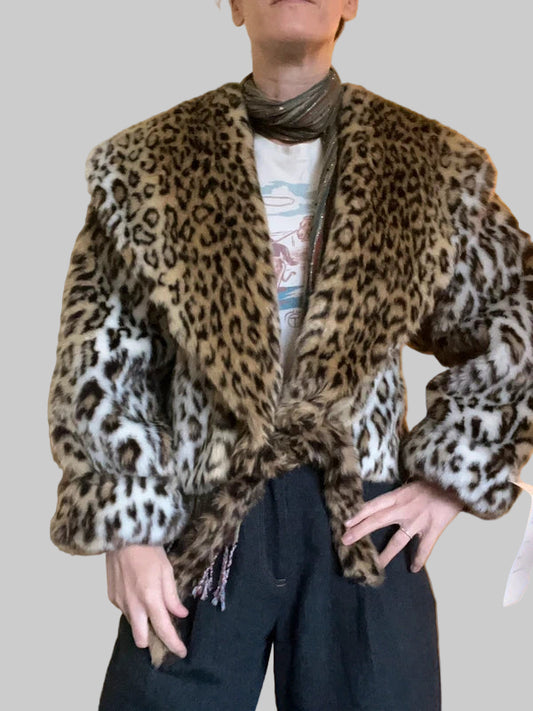 Person wearing a leopard print jacket over a graphic t-shirt against a plain background