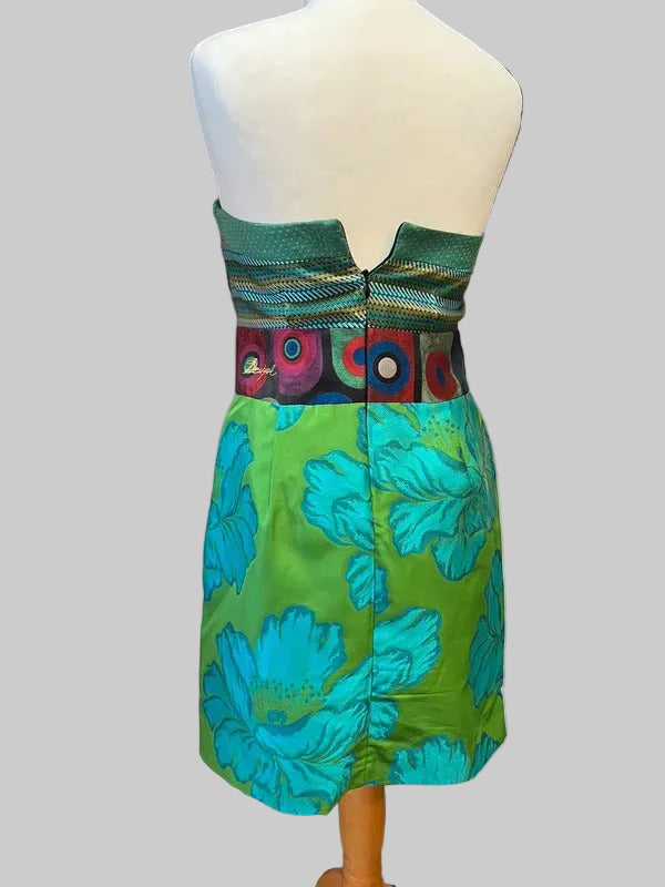A strapless dress displayed on a white mannequin torso, featuring a green and turquoise floral skirt with a patterned waistband in green, black, red, and white.